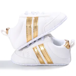 Vista detallada de zapatos blancos para bebé con rayas doradas y suelas de goma suaves
