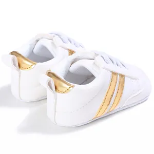 Detalle de la vista trasera de zapatillas blancas para bebé con rayas doradas y suela blanda