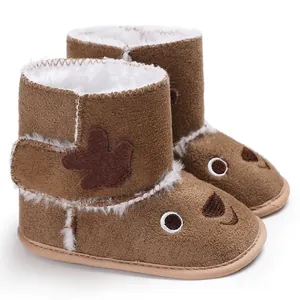 Close-up of brown baby winter boots with cute cartoon face and warm faux fur lining.