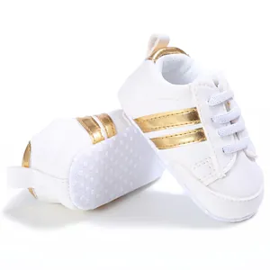 Vista detallada lateral y de la suela de estas zapatillas blancas para bebé con rayas doradas
