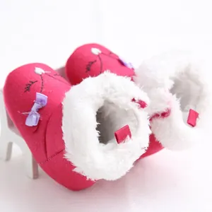 Close-up of pink infant snow boots with soft white faux fur lining and cute bow