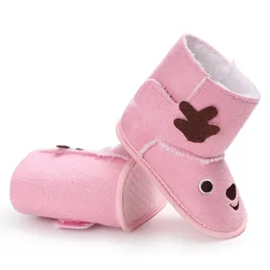 Close-up of pink baby winter boots with cute cartoon reindeer design and soft fleece lining