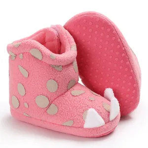Close-up of pink plush baby boots with cute white claw details and soft dot sole.