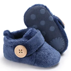 Close-up detail of soft navy blue fuzzy baby winter shoes featuring a wooden button and velcro