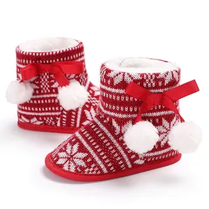 Close-up of festive red knitted baby boots with plush lining and white pom-poms