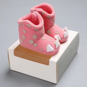 Close-up view of pink fuzzy baby winter claw boots resting on a white gift packaging box