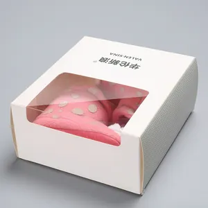 Macro view of pink polka dot baby winter boots inside a white windowed gift box
