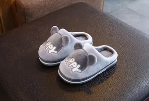 Gros plan de chaussons en peluche gris pour enfants avec motif chiot brodé.