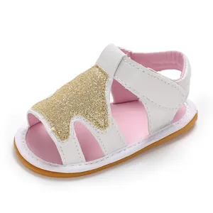 Primer plano de sandalias para bebé niña con estrella dorada brillante y cierre de velcro.