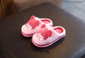 Gros plan de chaussons en peluche roses pour enfants avec broderie 'puppy' et oreilles.