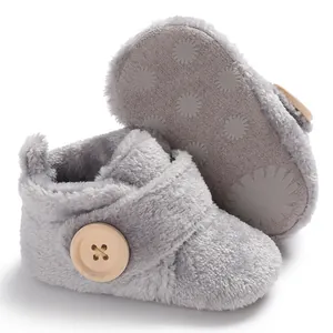 Detail view of grey plush baby booties featuring wooden button and non-slip sole design