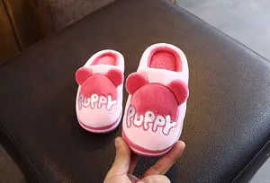 Gros plan détaillé de chaussons en peluche rose pour enfants avec broderie de chiot