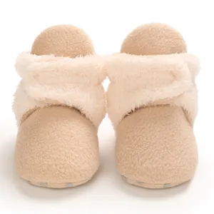 Primer plano de botas de nieve de forro polar beige para bebé con suela blanda antideslizante.