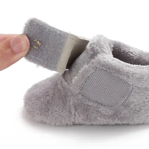Close-up detail of grey plush baby shoe showing soft texture and adjustable velcro strap