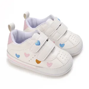 Close-up of white baby sneakers with colorful embroidered heart details and velcro