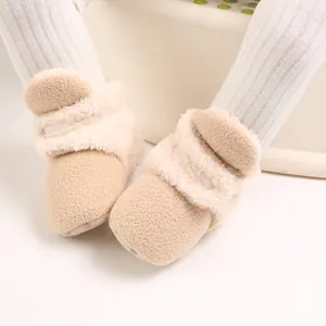 Primer plano de botas de nieve para bebé en forro polar beige con suela blanda y piel sintética