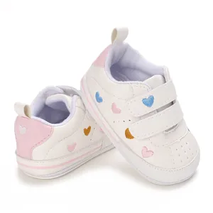 Detailed view of white toddler sneakers featuring colorful heart embroidery and dual velcro straps