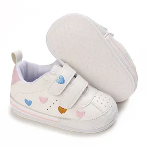 Detail shot of white baby sneakers featuring colorful heart embroidery and anti-slip outsoles