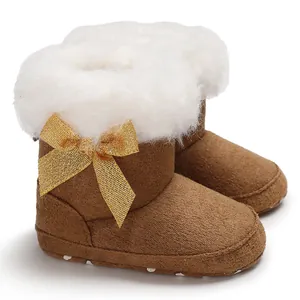 Detail of baby snow boots with white faux fur trim and golden glittery bow
