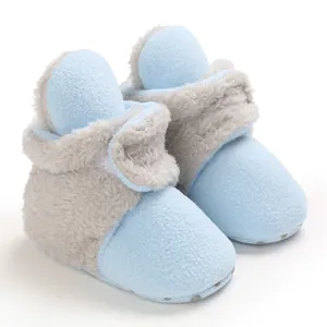 Primer plano de botas de nieve para bebé de forro polar azul con forro de piel sintética gris.
