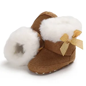 Macro view of warm brown baby snow boots with fluffy white faux fur and gold bow