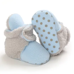 Vue détaillée de chaussons pour bébé en peluche bleu et gris avec semelles antidérapantes