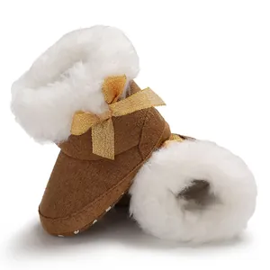 Macro view of cozy brown baby snow boots featuring white fleece lining and a glittery gold bow
