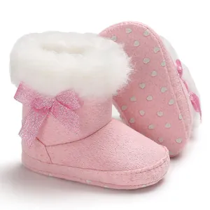 Pink baby snow boots with white faux fur trim and sparkling bow detail on white background