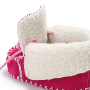 Dettaglio macro di scarpa neonato rosa con calda fodera in pile bianco e morbido camoscio.