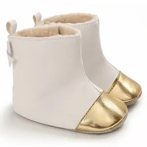 Detail view of white baby winter boots featuring gold toe caps and warm faux fur lining