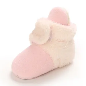 Detalle de vista lateral de botas de nieve de felpa rosa y crema para bebé en invierno