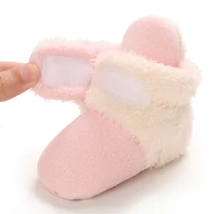 Primer plano de botines de lana rosa para bebé con cierre de velcro y ribete de pelo suave