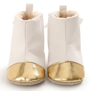 Close-up front view of white baby winter boots featuring a gold metallic toe and warm fleece lining