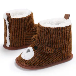 Close-up detail of cozy brown knitted baby snow boots with warm fleece lining and bear face.