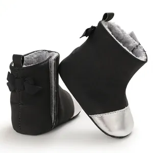 Close-up detail of black winter baby boots with silver metallic toe and bow decoration