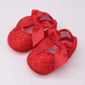 Primer plano de zapatos de encaje rojo para bebé con lazos de cinta grandes