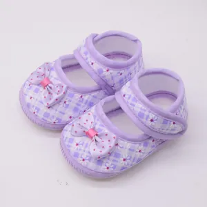 Draufsicht auf lila karierte Babyschuhe mit Blumenmuster und rosa Schleife.