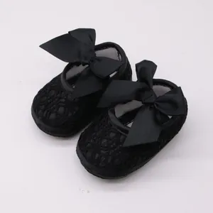 Detalle de zapatos de princesa para bebé niña en encaje negro con un gran lazo