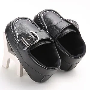 Close-up detail of black faux leather baby loafers with white stitching and buckle