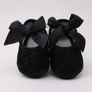 Vista detallada de zapatos de encaje negro para bebé con grandes lazos decorativos