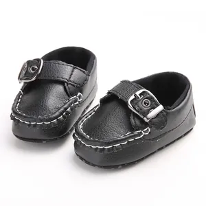 Close-up of black PU leather baby shoes with buckle strap and white stitching