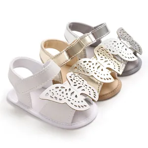 Detalle de sandalias para bebé con diseño de mariposa cortado con láser en blanco, oro y plata.