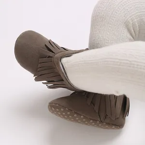 Detailed view of baby brown tassel snow boots with soft dotted anti-slip soles.