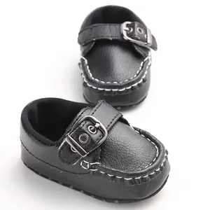 Detailed view of black baby moccasin shoes with buckle strap and white stitching
