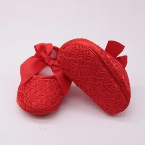 Primer plano de zapatos de princesa rojos de encaje para bebé con gran lazo.