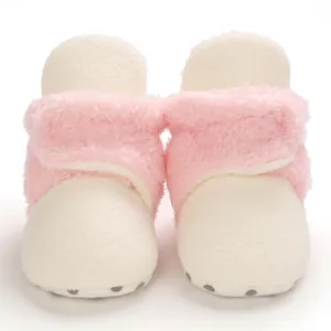 Vista frontal de botas de nieve para bebé en felpa rosa y crema con suelas antideslizantes.