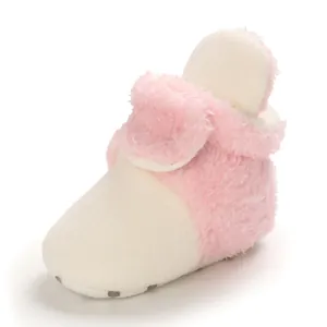 Primer plano de botas de nieve suaves y peludas rosa y blanco para bebé con suela antideslizante