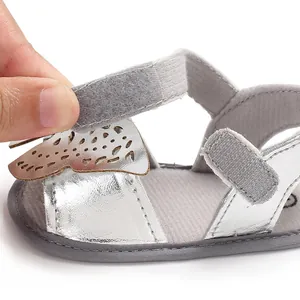 Primer plano de la sandalia plateada para bebé con cierre de velcro y detalle de mariposa