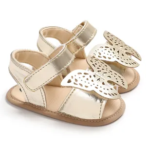 Detalle de sandalias doradas para bebé con mariposa y suelas de silicona suave antideslizantes.