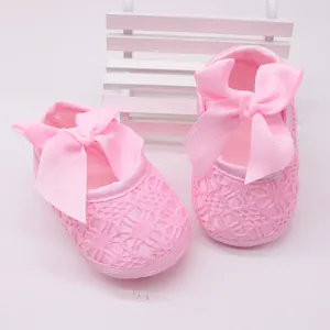 Vista detallada de zapatos de princesa para bebé en encaje rosa con lazos grandes